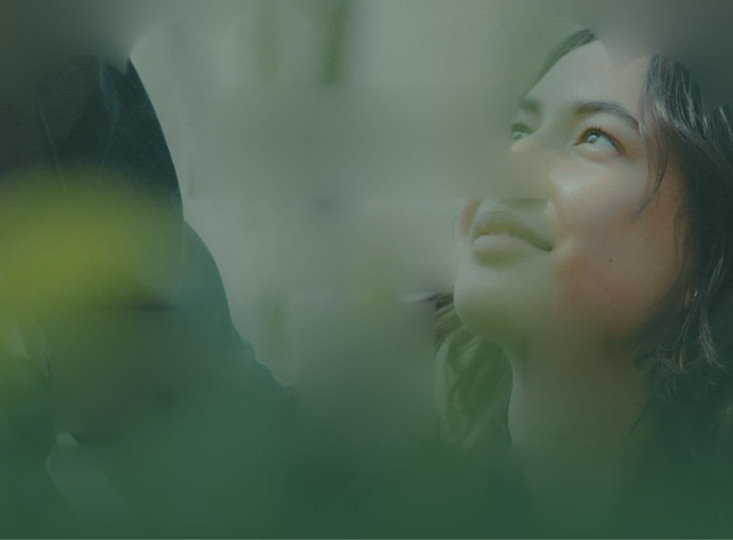Woman looking up, surrounded by green leaves